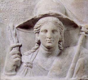 Η Ίσιδα-Δήμητρα φορώντας το συμβολικό ένδυμα με τον ισιακό κόμβο, κρατώντας σιτάρι και σκήπτρο, σε ανάγλυφο από το Δίον.