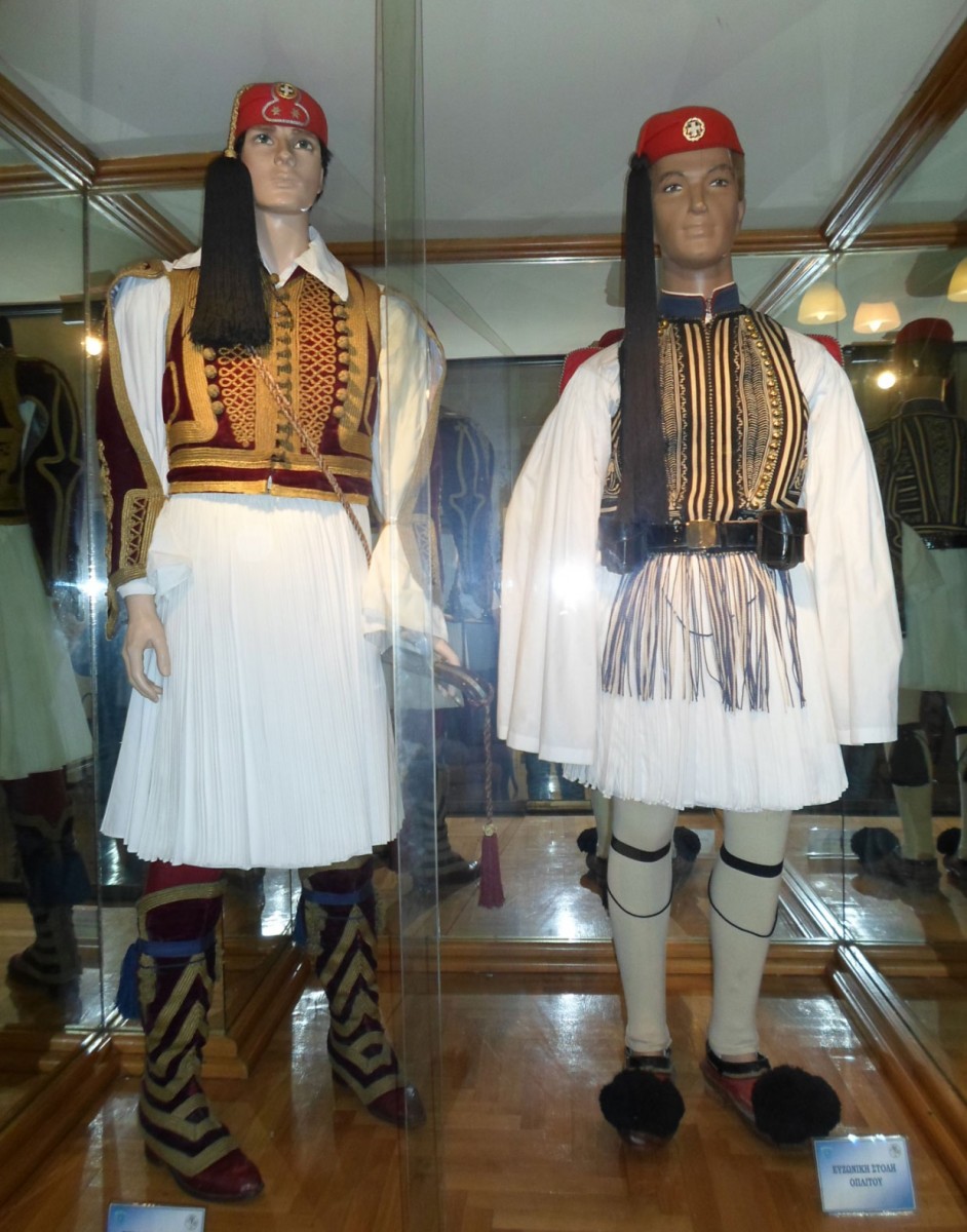 Η στολή του εύζωνα αξιωματικού (αριστερά) και η στολή του εύζωνα οπλίτη (δεξιά) σε προθήκη στο γραφείο Διοίκησης της προεδρικής Φρουράς (φωτ.: Διεύθυνση Νεώτερου Πολιτιστικού Αποθέματος και Άυλης Πολιτιστικής Κληρονομιάς/ΥΠΟΠΑΙΘ).