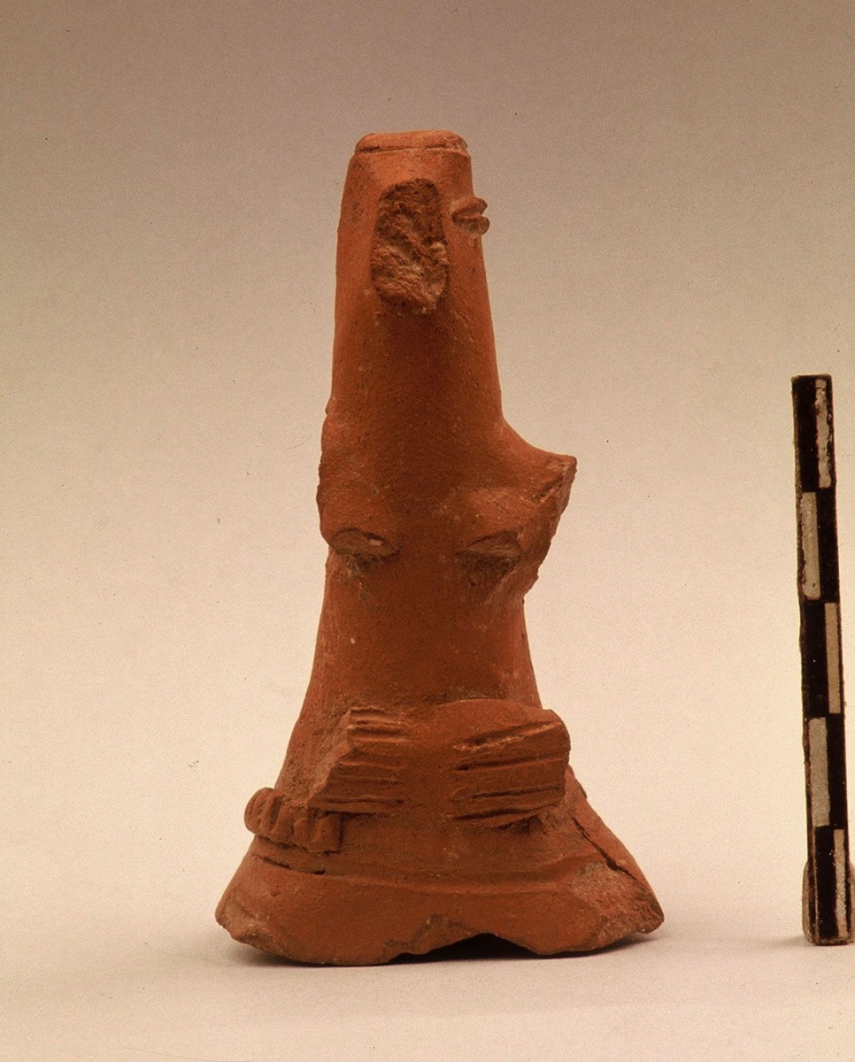 Εικ. 36. Ειδώλιο με ενδυμασία και κόμμωση (κότσο) στο πίσω μέρος της κεφαλής. Η βάση του σπασμένη, πιθανόν χρησίμευε ως λαβή σε πώμα αγγείου. Μάλλον Χαλκολιθικής περιόδου.