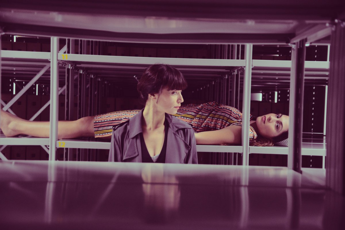 Οι δύο ερευνήτριες μυούν τους επισκέπτες στα άδυτα του Αρχείου. Διεισδύουν τόσο βαθιά σε αυτό που μελετούν, που σταδιακά μεταλλάσσονται, ταυτίζονται και γίνονται οι ίδιες το αντικείμενο της έρευνάς τους. Χαρίζοντας φωνή σε ψίθυρους από το παρελθόν.