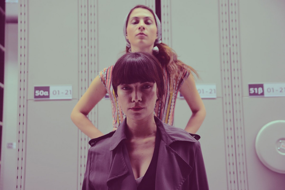 Στα πρώτα λεπτά της συνάντησης, η μία καταγράφει το όνομα κάθε επισκέπτη και η άλλη χωρίζει τους θεατές σε δύο ομάδες: τους «Εργαζόμενους» και τους «Βιομήχανους». Κάθε θεατής φέρει πλέον ένα διακριτικό. Όλοι μαζί προχωρούν στο εσωτερικό του πρώην βιομηχανικού κτηρίου.