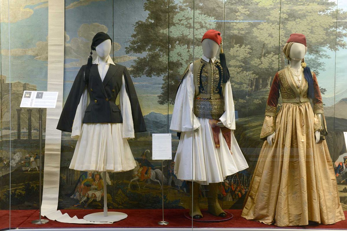 Αριστερά: Jean Paul Gaultier, «Υψηλή Ραπτική Άνοιξη-Καλοκαίρι 2006». Συλλογή «Αφιέρωμα στην Ελλάδα». Μοντέλο «Παρίσι-Αθήνα». Σταυρωτό σακάκι με μανίκια σε στυλ «κάπα» από μαύρο μαλλί «Σαντορίνη». Φόρεμα «φουστανέλα» με πτυχώσεις από οργάντζα στο χρώμα του καλαμποκιού.