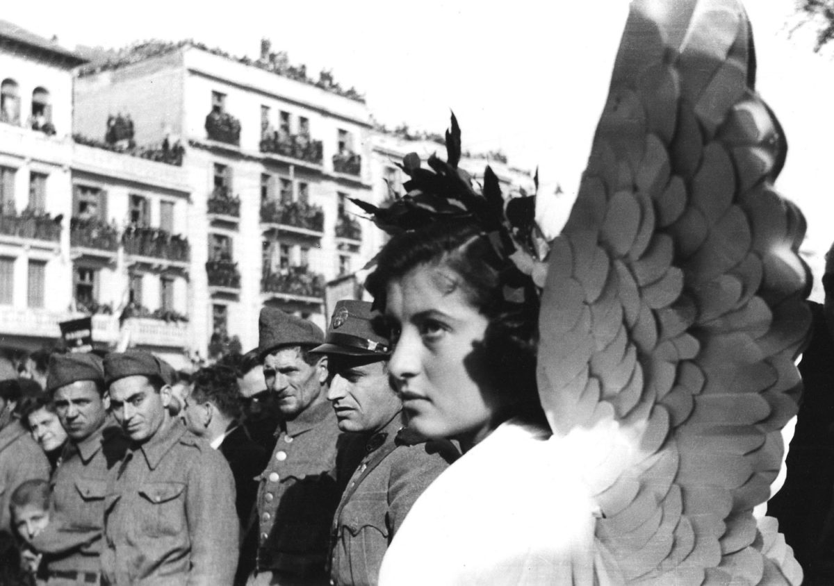 Αγνώστου φωτογράφου. Δρώμενο ή ταμπλό βιβάν, με κορίτσια ντυμένα αγγέλους, μπροστά σε στρατιώτες του ΕΛΑΣ και αστυνομικούς, 1944. Μουσείο Φωτογραφίας Δήμου Καλαμαριάς «Χρήστος Καλεμκερής». Πηγή φωτ.: ΠΕΕΒΕ.