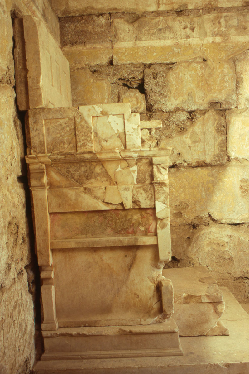 Πλάγια όψη του θρόνου του τάφου με την ιωνική πρόσοψη που αποκάλυψε ο καθ. Κ. Ρωμαίος στη Βεργίνα το 1938, εγκαινιάζοντας με το εύρημα αυτό την Πανεπιστημιακή Ανασκαφή Βεργίνας, εκ μέρους του ΑΠΘ. Έχει ύψος 1,98 μ. και πλάτος 0,95 μ. Μπροστά από τον θρόνο υπάρχει μαρμάρινο υποπόδιο. 