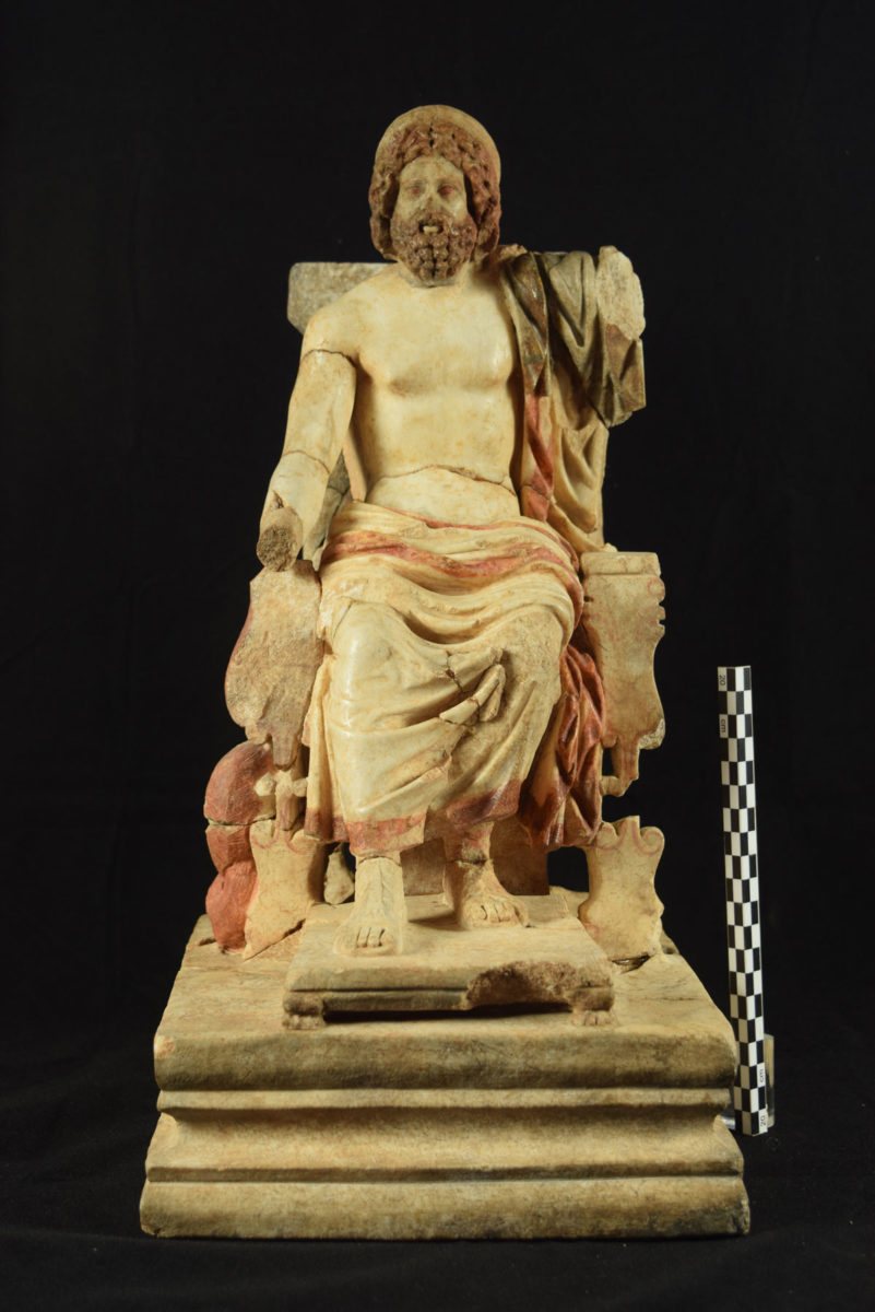 Μαρμάρινο αγαλμάτιο ένθρονου Ασκληπιού, έργο αθηναϊκού εργαστηρίου στο πρότυπο του χρυσελεφάντινου αγάλματος του θεού που είχε φιλοτεχνήσει ο πάριος γλύπτης Θρασυμήδης στην Επίδαυρο. 150–200 μ.Χ. © Αρχαιολογικό Μουσείο Αρχαίας Κορίνθου (φωτογραφικό αρχείο).