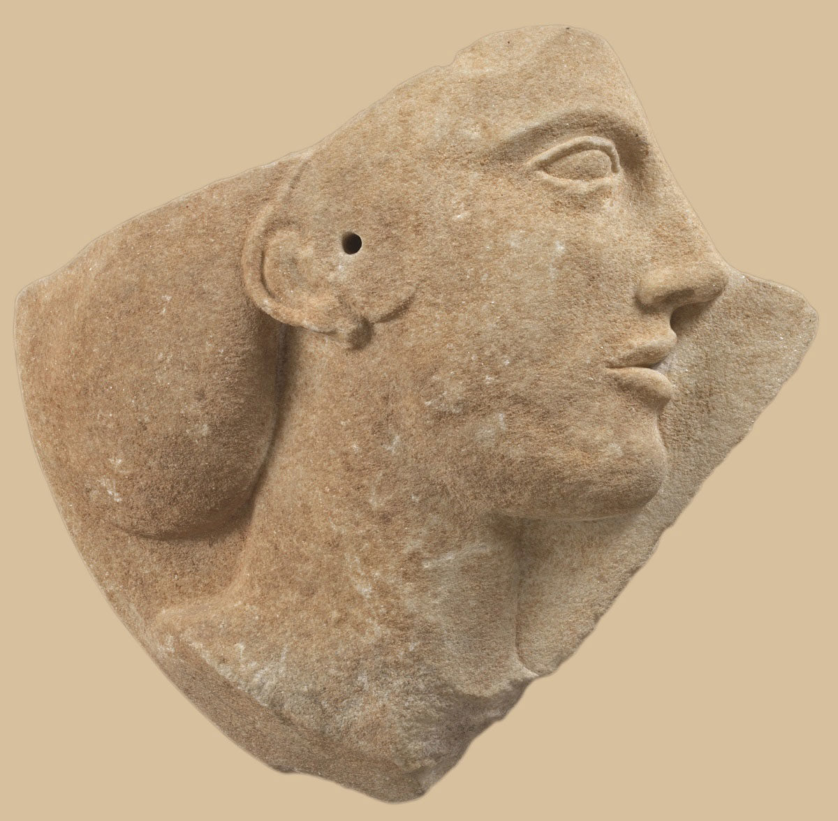 Τμήμα μαρμάρινου δίσκου με ανάγλυφη γυναικεία κεφαλή, πιθανώς η Αφροδίτη. Από τη Μήλο. Γύρω στο 460-450 π.Χ. (φωτογράφος: Γιάννης Πατρικιάνος). © Εθνικό Αρχαιολογικό Μουσείο/ΤΑΠ.