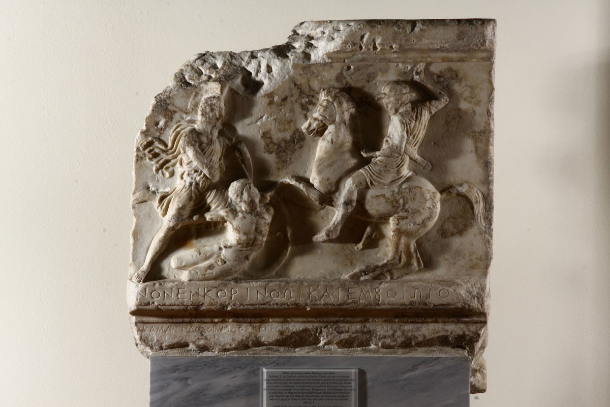 Άνω τμήμα του επιτύμβιου μνημείου που έστησαν οι Αθηναίοι για να τιμήσουν τους πεσόντες στις μάχες της Κορίνθου και της Κορώνειας το 394 π.Χ. Βρέθηκε στο Δίπυλο το 1907. Στον κανόνα κάτω η επιγραφή ΑΠΕΘΑ]ΝΟΝ ΕΝ ΚΟΡΙΝΘΩΙ ΚΑΙ ΕΝ ΒΟΙΩΤΟΙ[Σ]. (© TAΠΑ/Εθνικό Αρχαιολογικό Μουσείο)