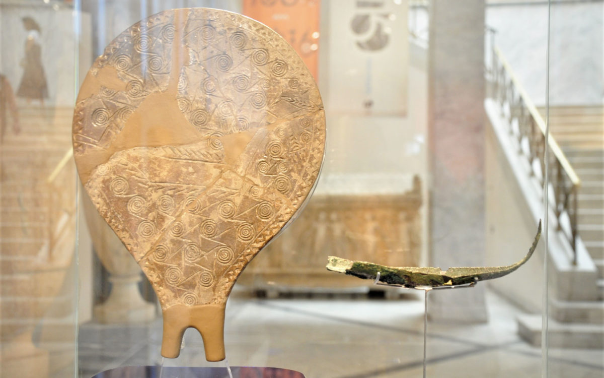 Πήλινο τηγανόσχημο σκεύος από τη Χαλανδριανή Σύρου, 2800-2300 π.Χ. (Πρωτοκυκλαδική ΙΙ περίοδος) (ΕΑΜ Π 6177.1 © TAΠΑ/Εθνικό Αρχαιολογικό Μουσείο) και χάλκινο ομοίωμα λέμβου από την Κέα, 16ος αι. π.Χ. (Υστεροκυκλαδική Ι περίοδος) (ΕΑΜ Π 21532 © TAΠΑ/Εθνικό Αρχαιολογικό Μουσείο). 