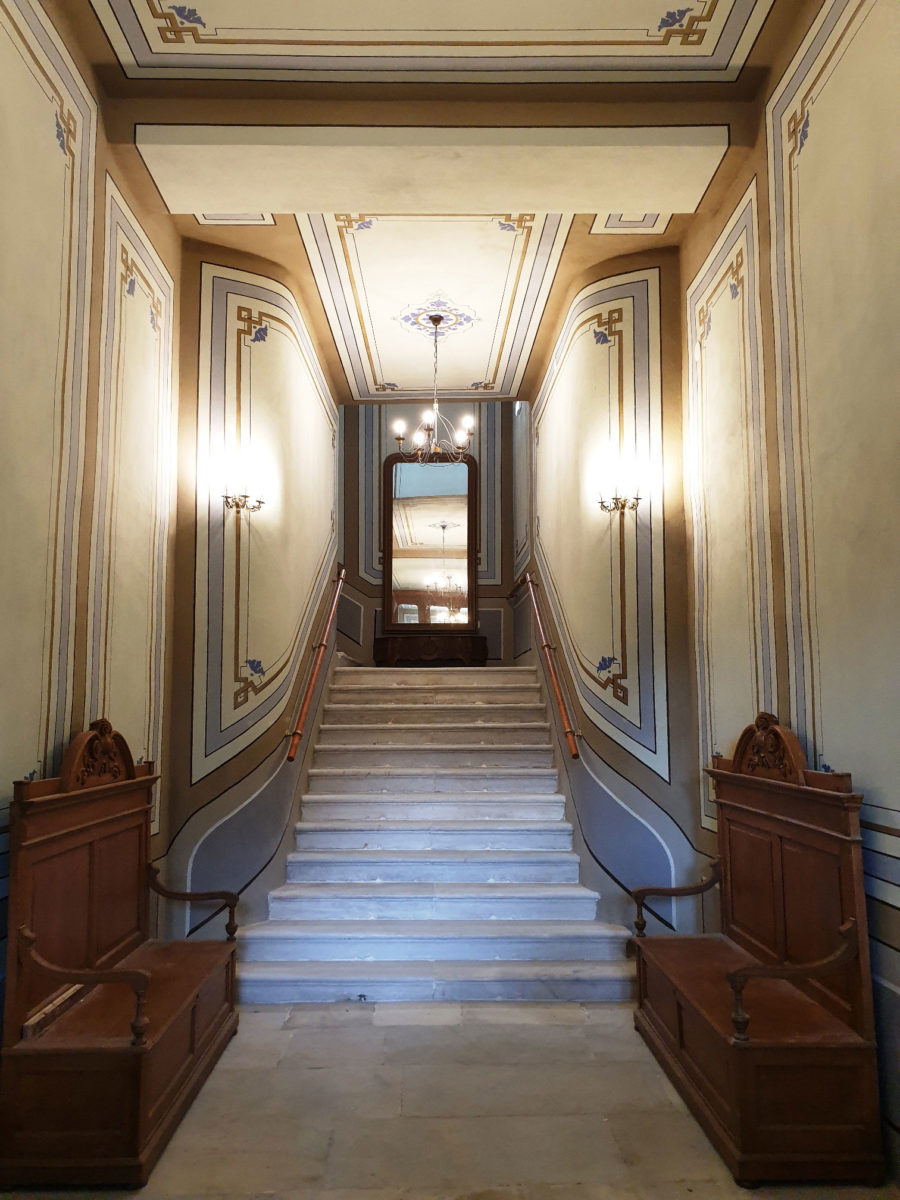 Η μεγαλοπρεπής ξύλινη είσοδος του κτιρίου με τη μαρμάρινη σκάλα και τις αποκαλυφθείσες τοιχογραφίες δίνουν πλέον στον επισκέπτη την αίσθηση ότι εισέρχεται σε βιενέζικο παλάτι (φωτ.: ΑΠΕ-ΜΠΕ).