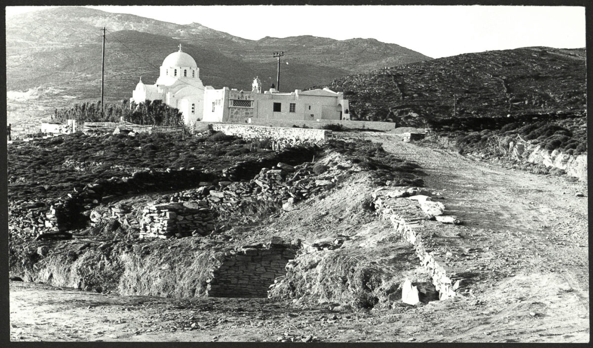 Άποψη της ανασκαφής στην Αγία Θέκλα, στην Τήνο, το 1979. Διακρίνονται τα υπολείμματα του θολωτού τάφου (κάτω) και η ομώνυμη εκκλησία (πάνω). © Αρχείο της εν Αθήναις Αρχαιολογικής Εταιρείας.