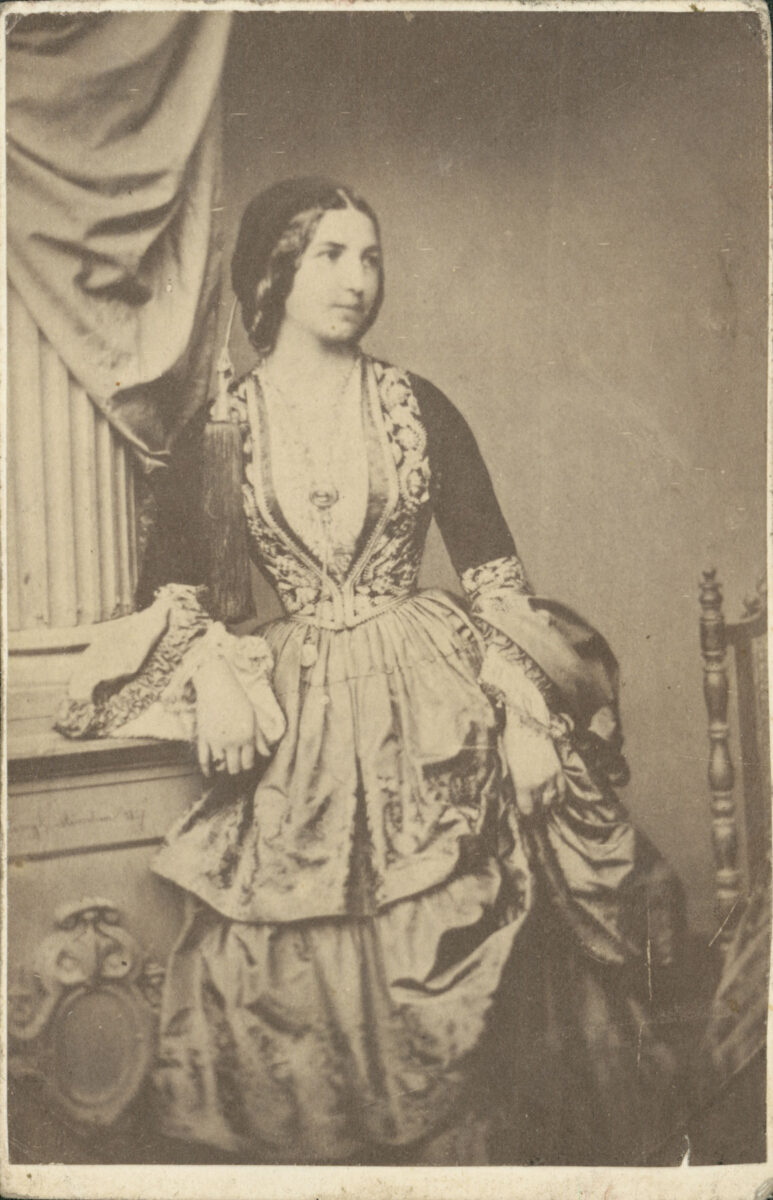 Άγνωστος φωτογράφος. Η Ασπασία Καρπούνη, κυρία επί των τιμών, με ενδυμασία της Αυλής της βασίλισσας Αμαλίας. Περ. 1860. Carte de visite, αλμπουμίνη. Μουσείο Μπενάκη / Φωτογραφικά Αρχεία.