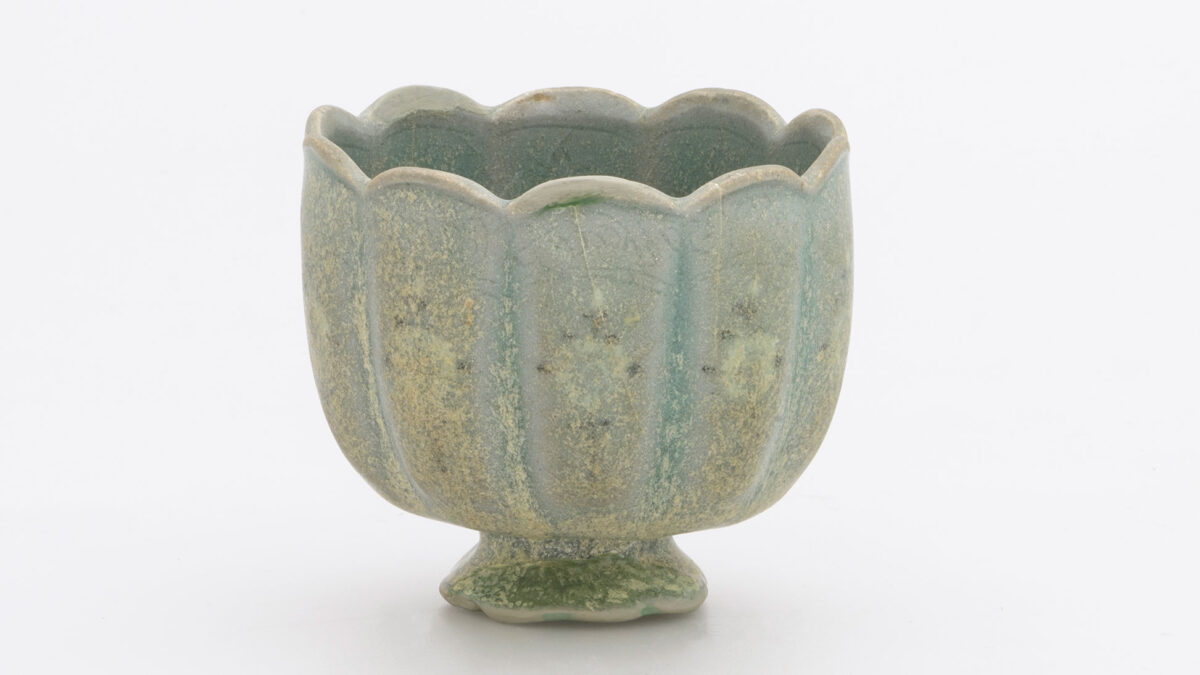 Κύπελο κρασιού. Σώμα με δέκα λοβούς και χαμηλό ανοιγόμενο πόδι από λιθοκέραμο με διακόσμηση εξωτερικά (πλοχμός κάτω από το χείλος και κλαδιά χρυσανθέμων παρακάτω) σε λευκό και μαύρο ένθετο αλοίφωμα κάτω από πράσινη εφυάλωση. Κορέα. Δυναστεία Κόρυο (918-1392), δεύτερο μισό 12ου αι. Διάμ. 7,4 εκ. Μουσείο Μπενάκη 2414. Δωρεά Γεωργίου Ευμορφόπουλου.