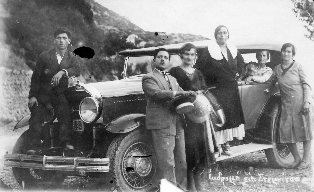Άνδρες και γυναίκες ποζάρουν ντυμένοι με τα καλά τους με το μοναδικό ταξί της Δημητσάνας. Ο Παναγόπουλος με την παρέα του αποφασίζουν να κάνουν μια βόλτα στη Στεμνίτσα και να απαθανατιστούν με το «θαύμα» της εποχής. Η φωτογραφία έχει ληφθεί κατά την περίοδο 1931-32. © Διασυνεδριακό και Πολιτιστικό Κέντρο Δημητσάνας.