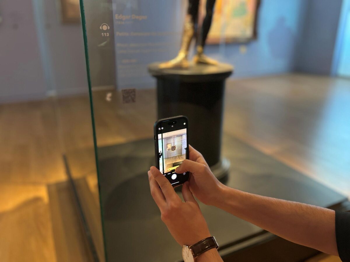 Οι επισκέπτες της μόνιμης Συλλογής του Ιδρύματος Β&Ε Γουλανδρή μπορούν να παρακολουθήσουν τις ξεναγήσεις στην Ελληνική Νοηματική Γλώσσα στους εκθεσιακούς χώρους, σκανάροντας με smartphone ή tablet τα ειδικά QR codes που βρίσκονται δίπλα στα αντίστοιχα έργα. Πηγή εικόνας: Ίδρυμα Β&Ε Γουλανδρή.