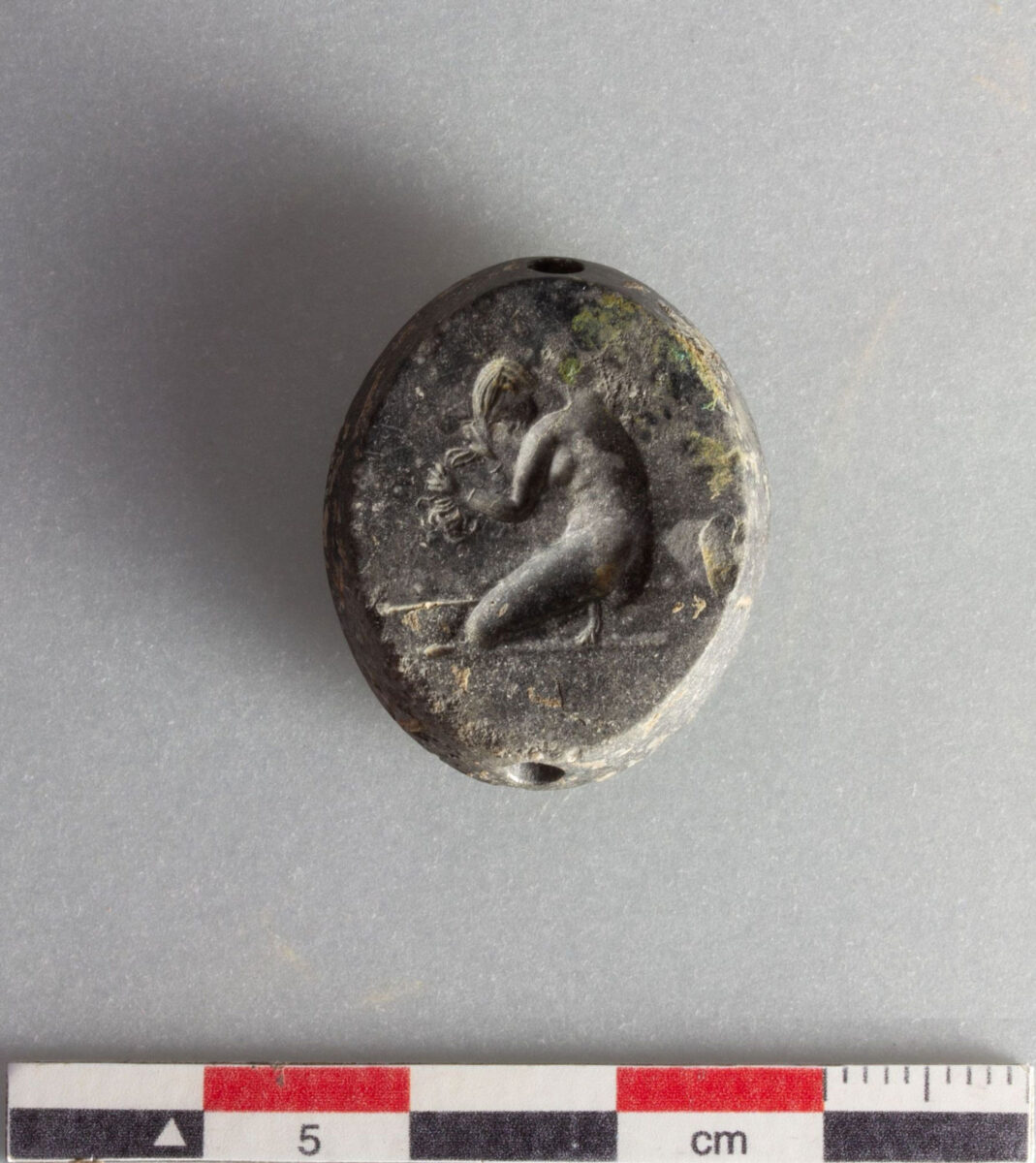 Σφραγιδόλιθος με παράσταση γονατιστής γυναίκας που λούζεται. Πηγή εικόνας: ΥΠΠΟ.